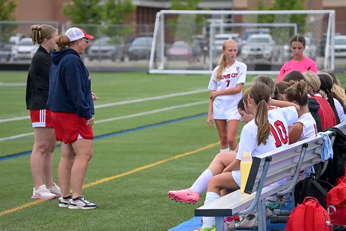 Coach Blount speaking with players beside the soccer field
